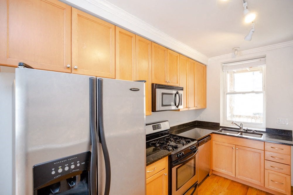 a kitchen with wooden cabinets and a stainless steel refrigerator