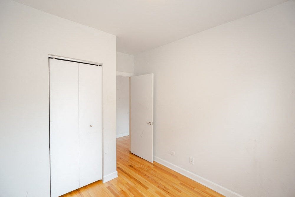 a bedroom with a closet and a wood floor