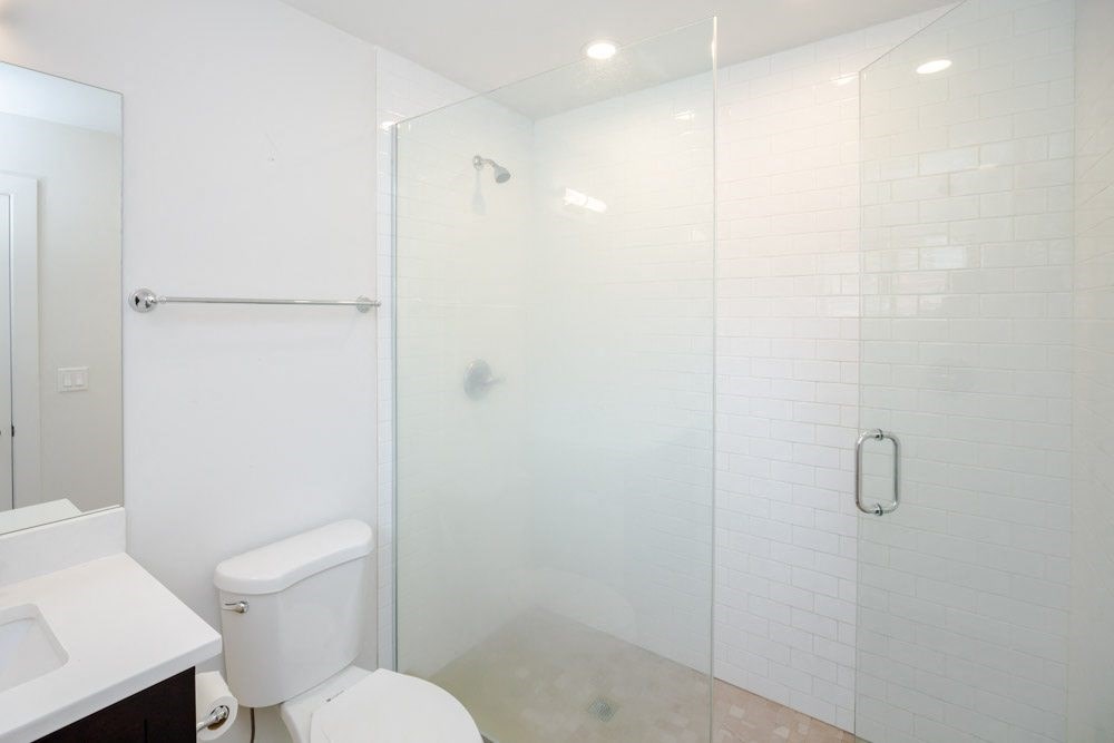 a white bathroom with a shower and a toilet