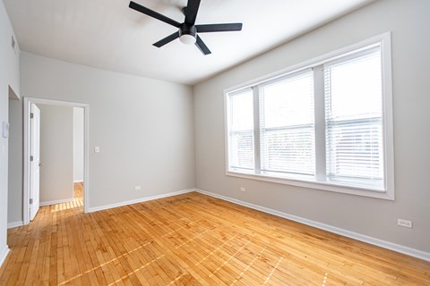 A room with a ceiling fan and a window with blinds.
