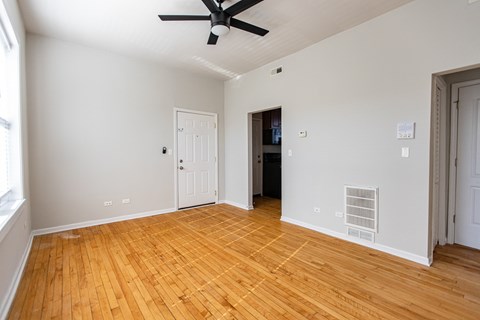 A room with a ceiling fan and wooden floors.