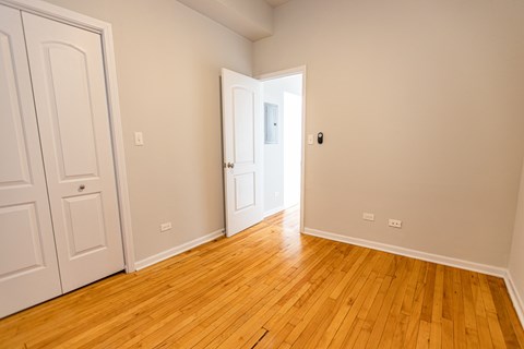A room with a white door and wooden flooring.