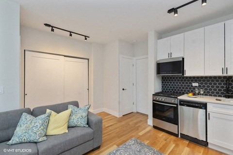 a living room with a couch and a kitchen with a stove
