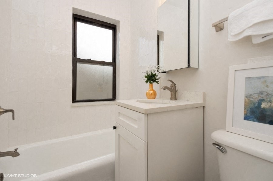 a white bathroom with a sink and a bath tub