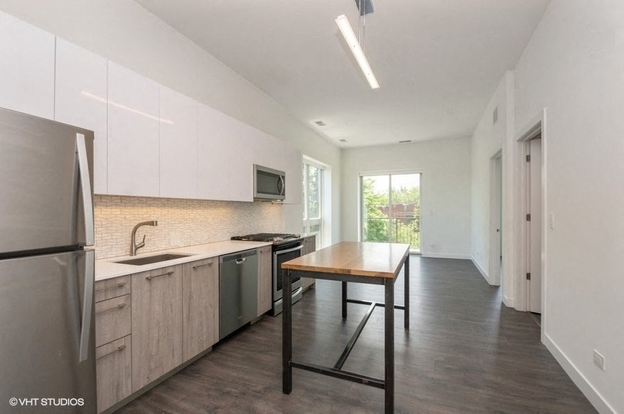 a kitchen with a table and a refrigerator and a sink