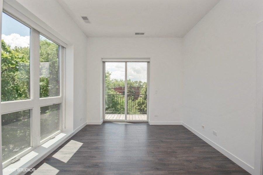 a living room with large windows and a door to a balcony