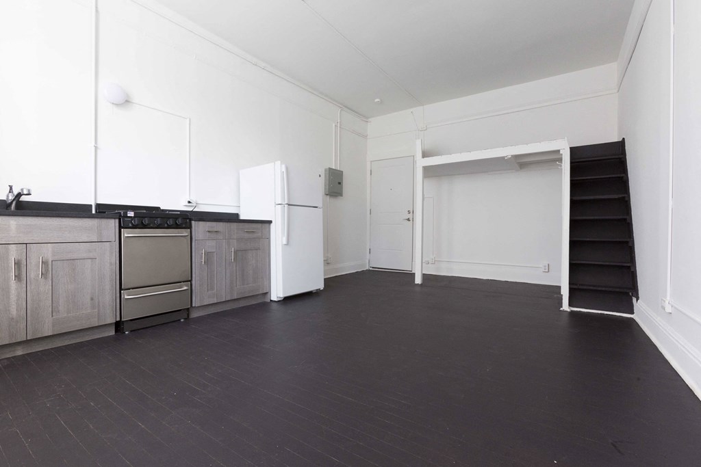 an empty room with a kitchen and a stove and a refrigerator
