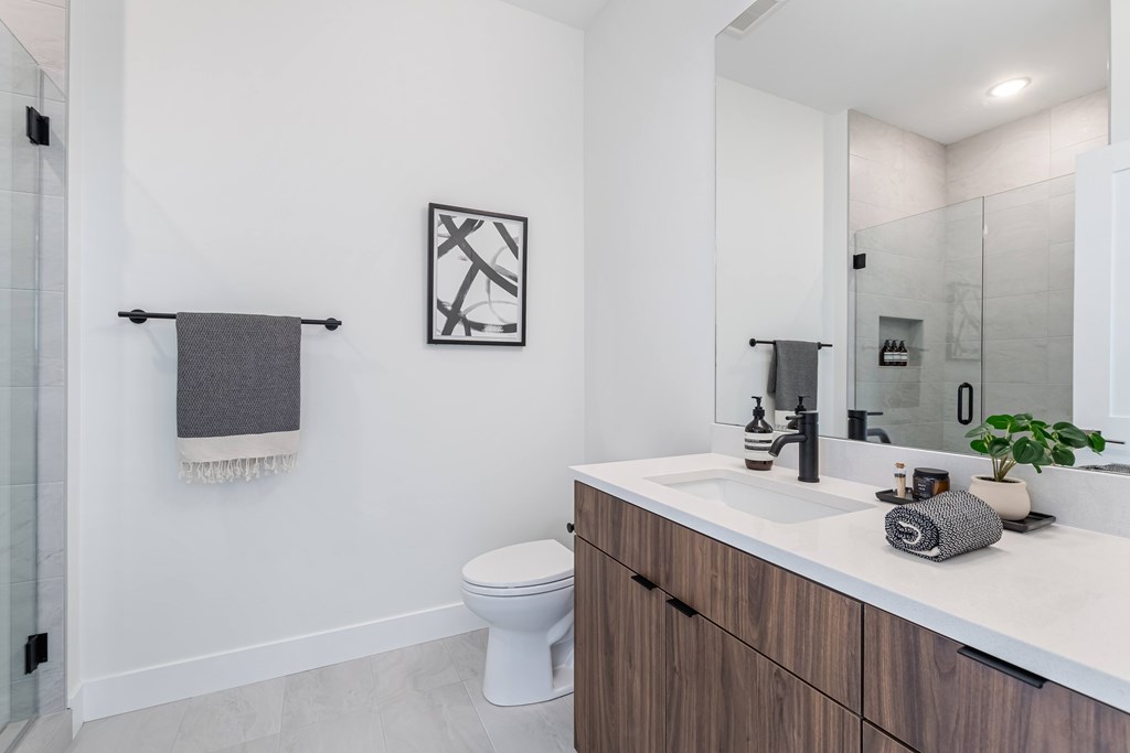 A bathroom with a toilet, sink, and mirror.