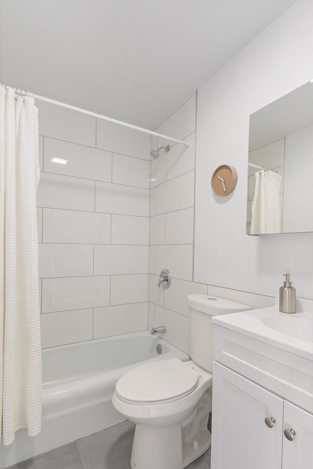a bathroom with white tiles and a white sink and toilet
