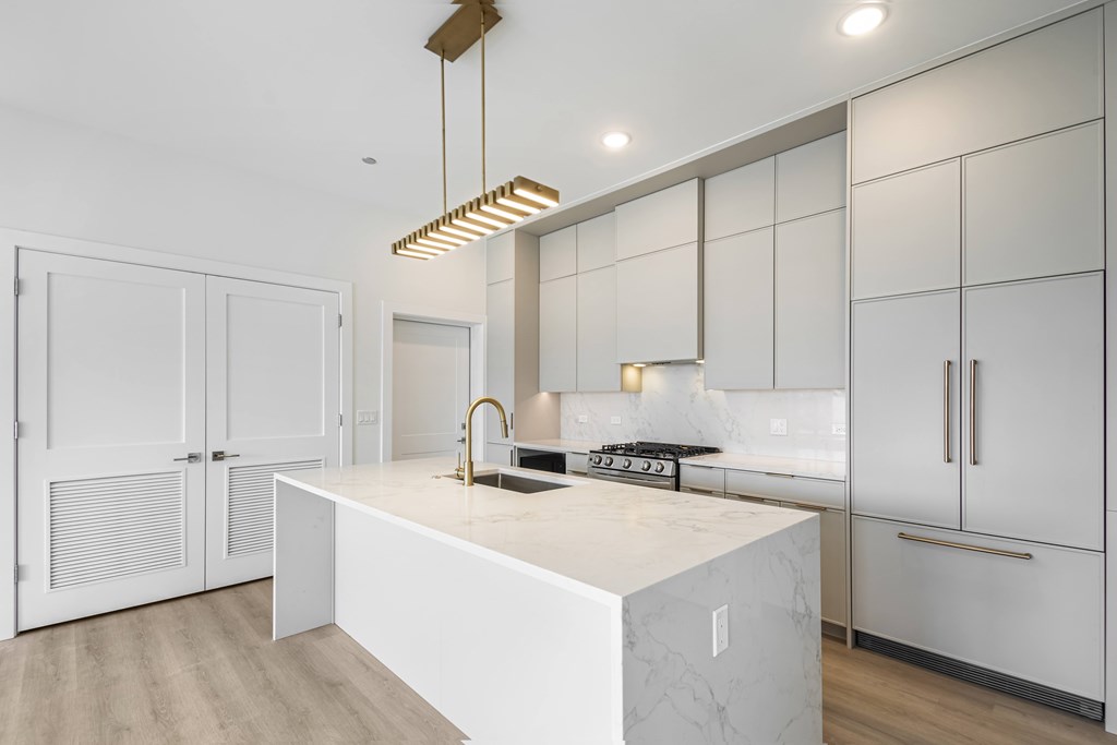 A modern kitchen with a white island and wooden floors.