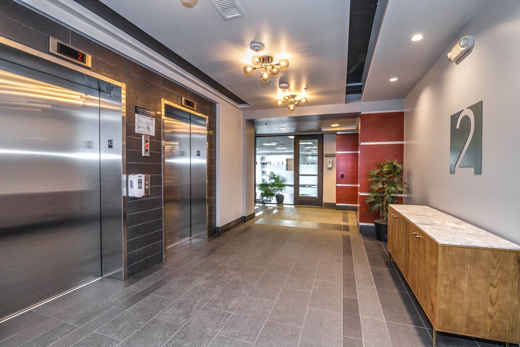 a hallway with elevators and a wooden bench in a lobby
