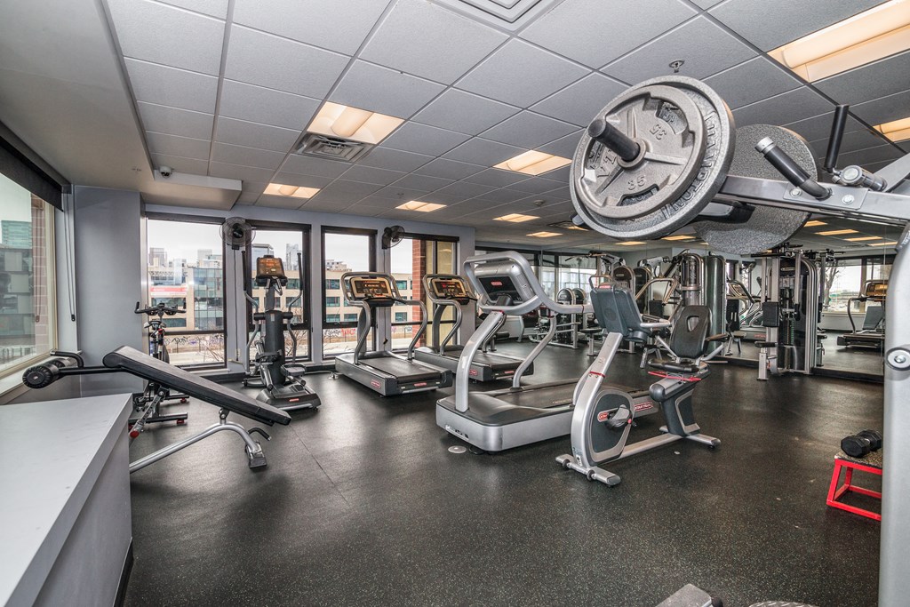a gym with weights and cardio equipment on the floor and windows