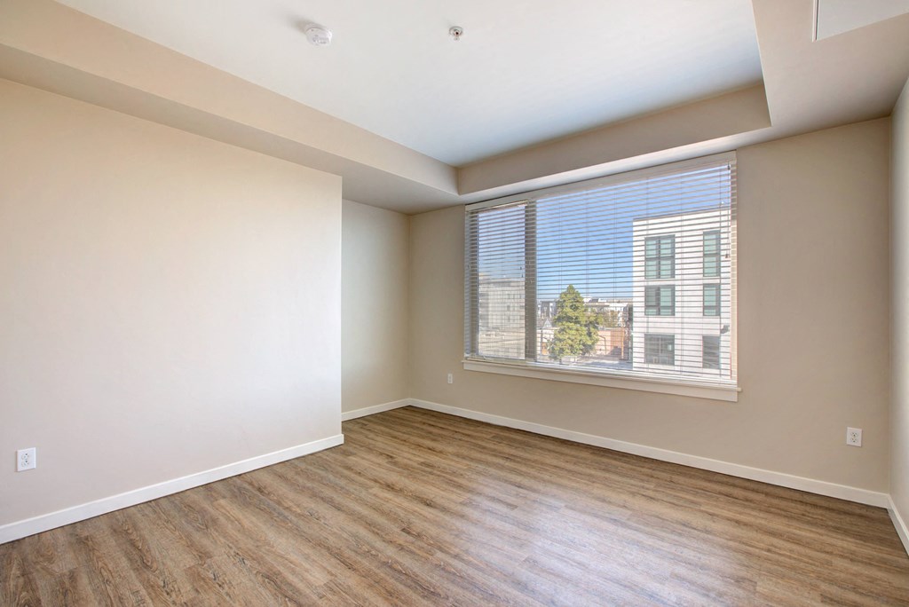 an empty living room with wood floors and a large window