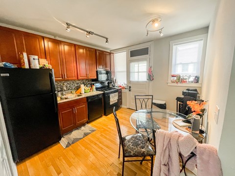 A kitchen with wooden cabinets and a black refrigerator.