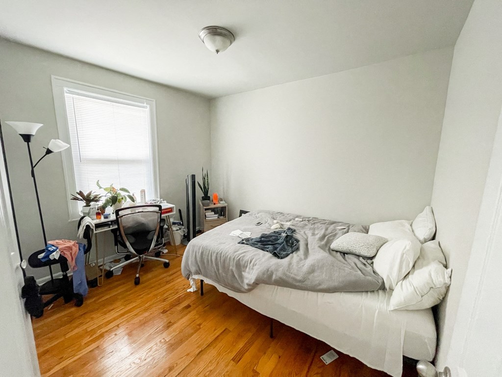 a bedroom with a bed and a desk and a window