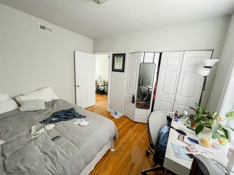 A bedroom with a bed, desk, and chair.
