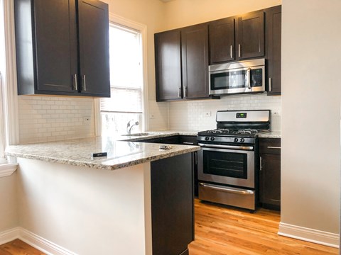 A kitchen with black cabinets and a granite countertop.