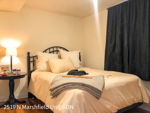 A bedroom with a bed, pillows, a nightstand, and a lamp.