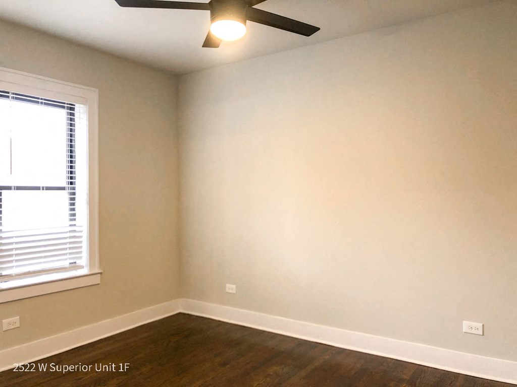 an empty room with a ceiling fan and a window