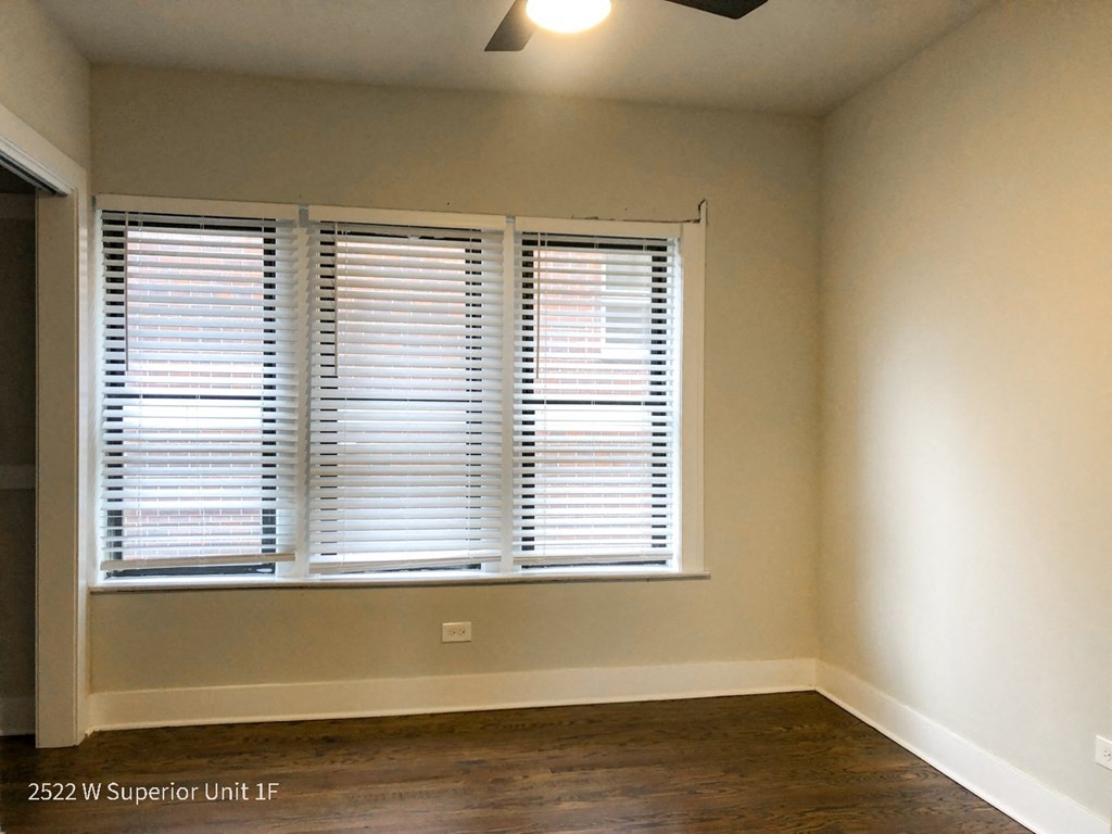 a bedroom with a large window and hardwood floors
