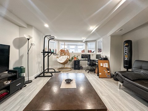 A living room with a brown rug in the middle of the wooden floor.