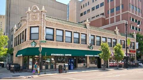 A Starbucks Coffee shop is located in a building with a green awning.