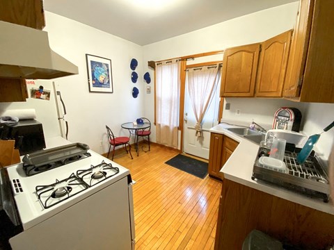 A kitchen with a stove, sink, and a dining table with chairs.