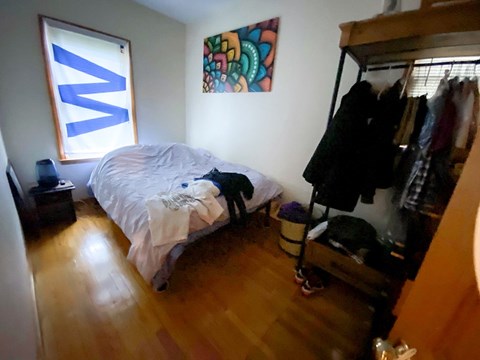 A bedroom with a bed, a wardrobe, and a painting on the wall.