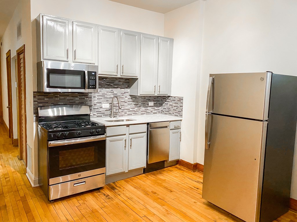 A kitchen with a refrigerator, stove, and microwave.