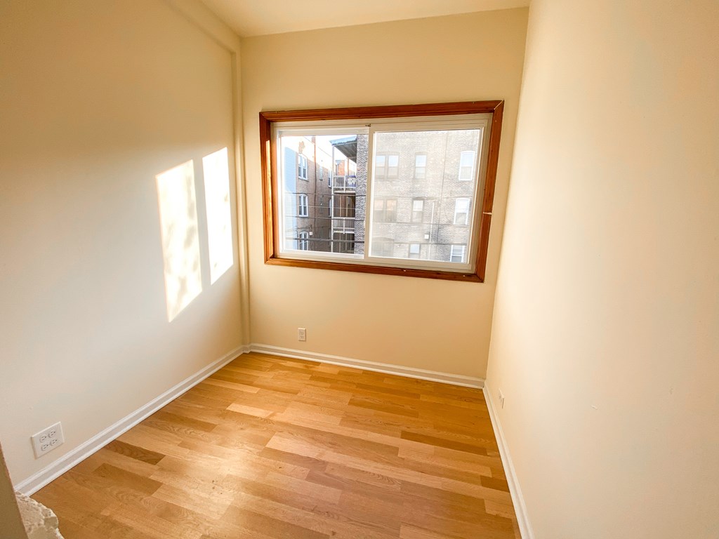 A room with a window and wooden flooring.