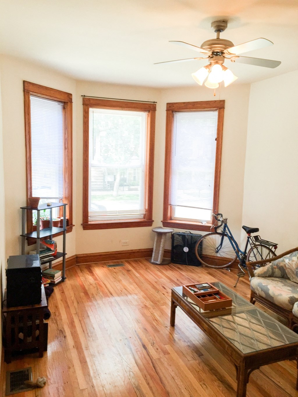 a living room with a couch and a bike in front of three windows