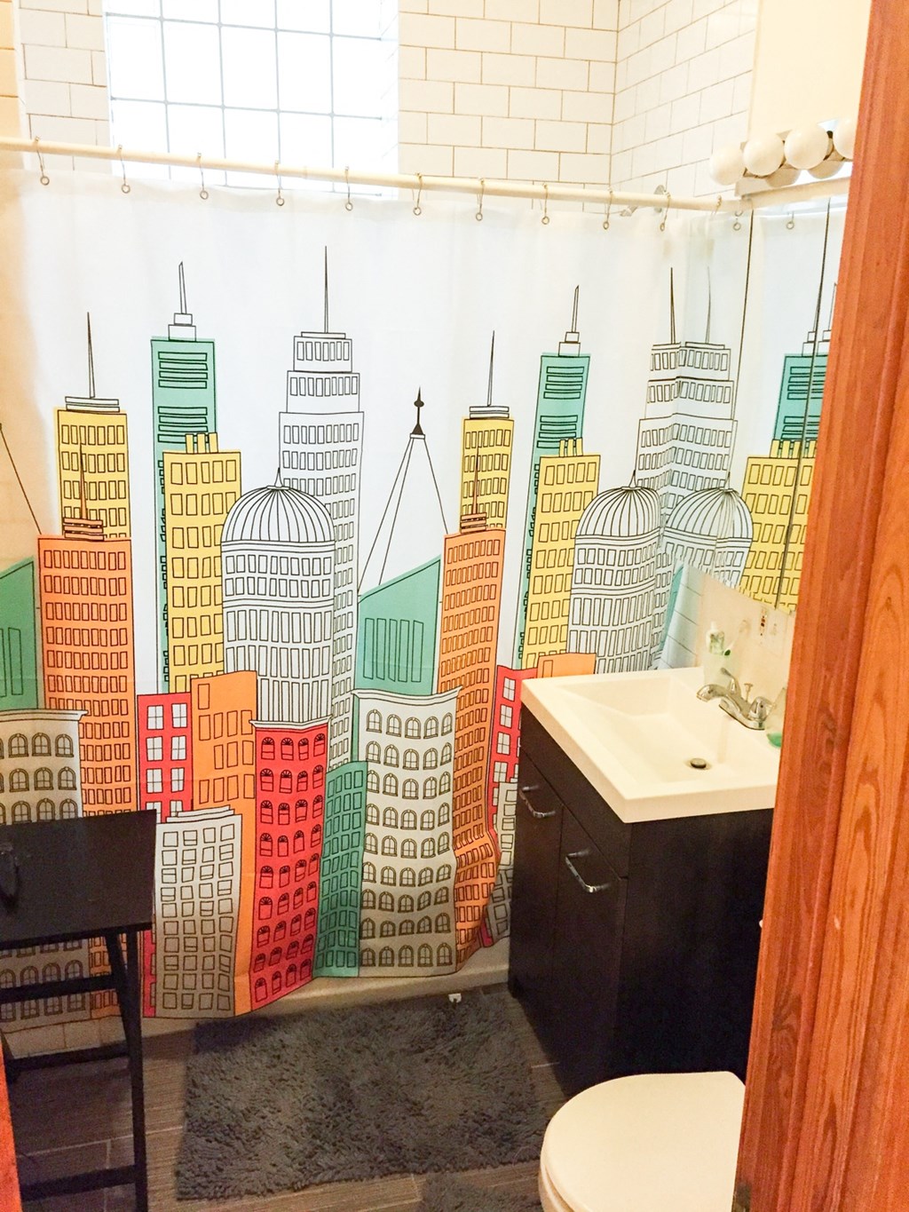 a bathroom with a shower curtain with a city skyline on it