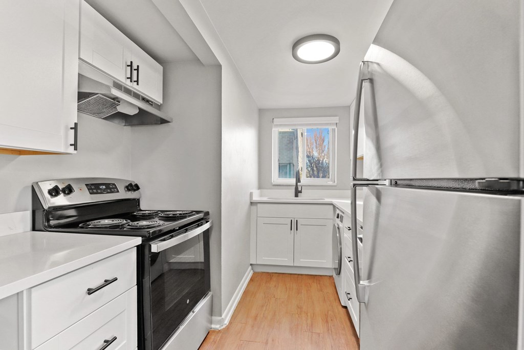 A small, modern kitchen with white cabinets and stainless steel appliances.