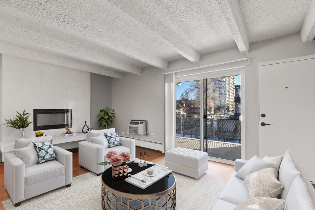A living room with white furniture and a large window overlooking a city.