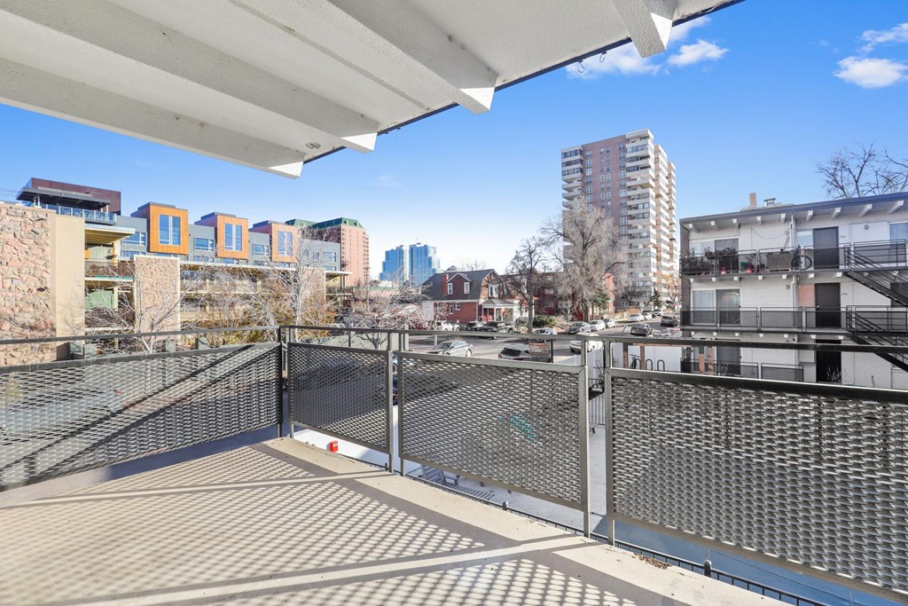 A balcony with a metal railing overlooks a cityscape.