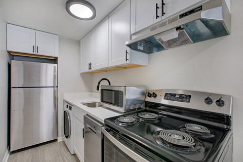 A modern kitchen with a stainless steel refrigerator, microwave, and oven.