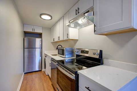 A kitchen with white cabinets and a stainless steel refrigerator.