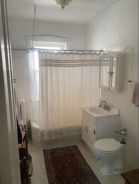 A white bathroom with a toilet, sink, and shower curtain.