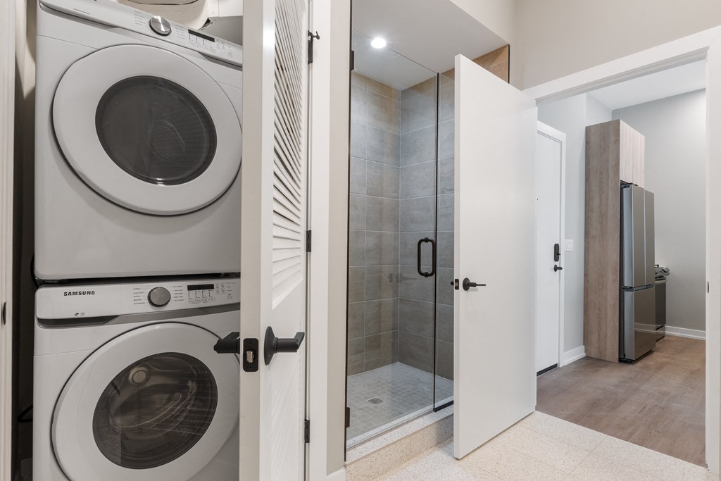 a washer and dryer in a bathroom next to a shower with a door