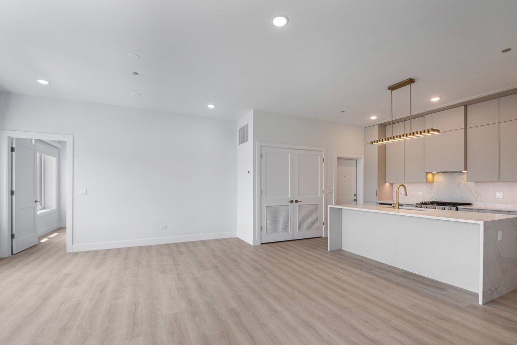 A modern kitchen with a white countertop and wooden flooring.
