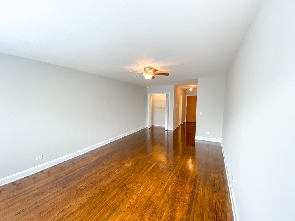 an empty living room with wood floors and a ceiling fan
