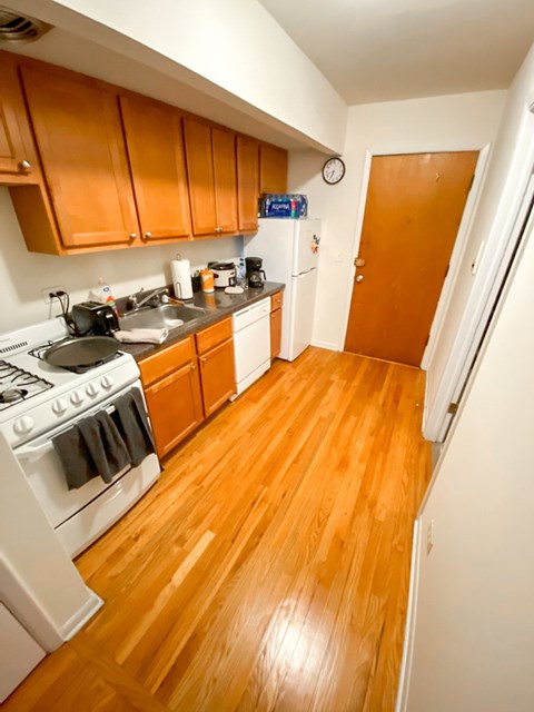 A kitchen with wooden floors and white appliances.