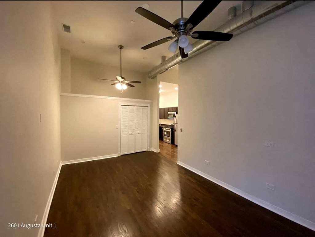 an empty living room with a ceiling fan and wood floors
