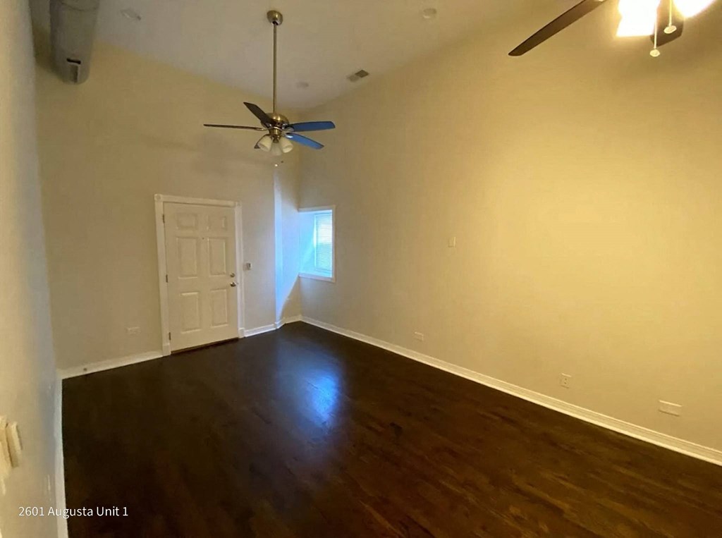 a empty living room with wooden floors and a ceiling fan