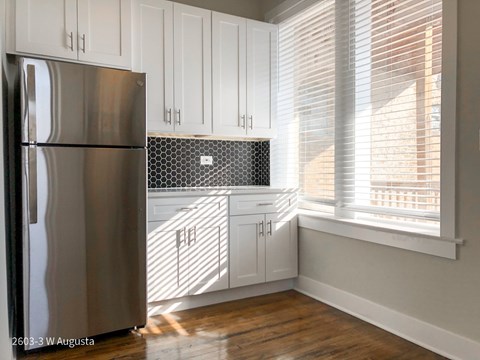 A kitchen with a stainless steel refrigerator and white cabinets.