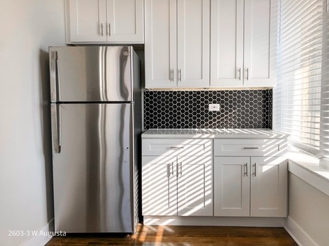 A kitchen with white cabinets and a stainless steel refrigerator.