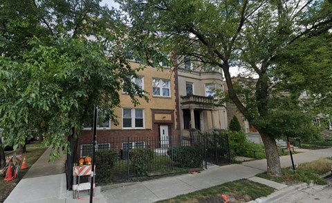 A tree is in front of a two-story house.