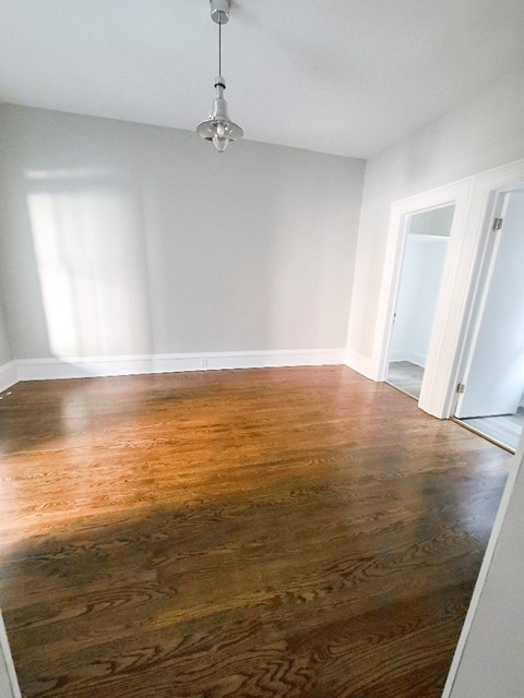A room with a wooden floor and a light hanging from the ceiling.