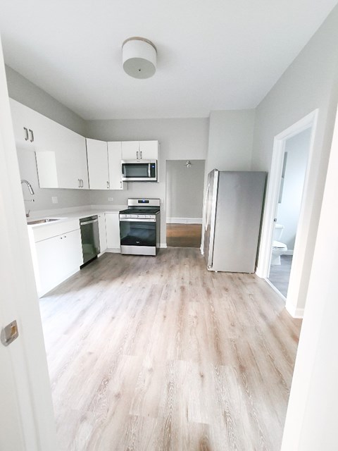 A kitchen with white cabinets and a refrigerator.