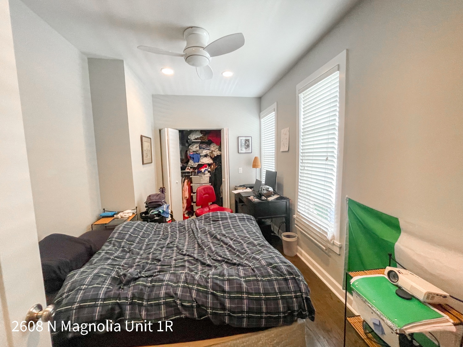 a bedroom with a bed and a closet with clothes on it